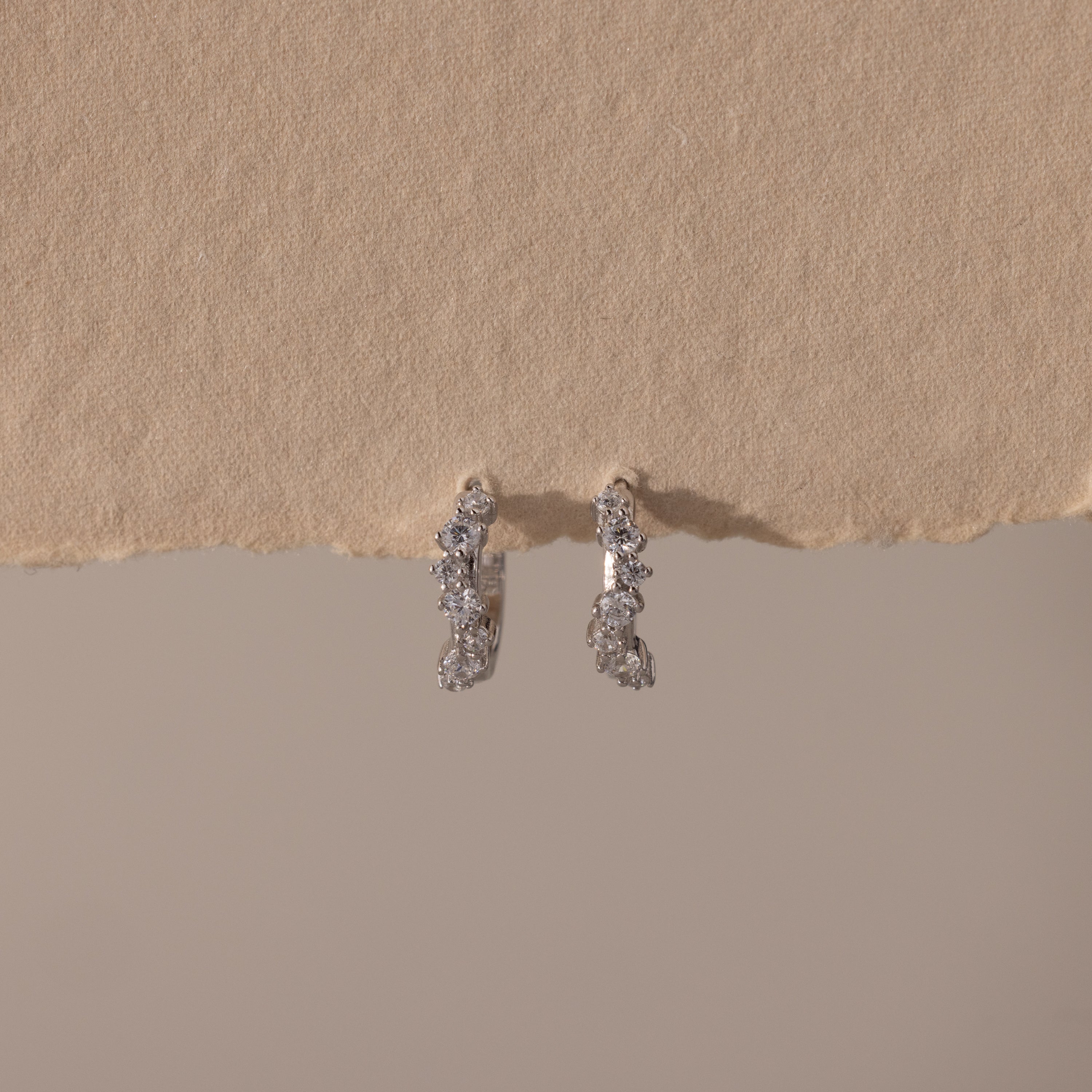 Marquise Cluster Hoop Earrings in silver with clustered CZ diamond stones, displayed on a neutral surface.