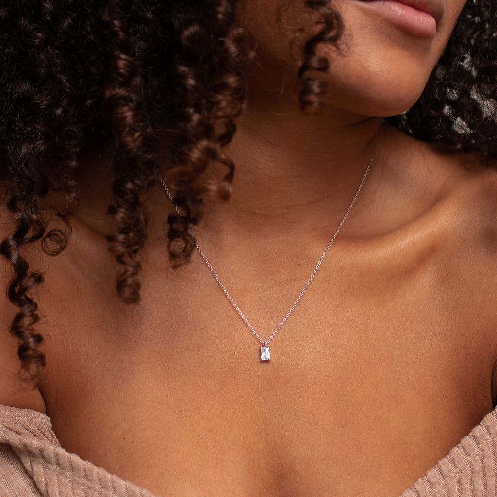 Close-up of a woman wearing the Sage Diamond Necklace in Silver, highlighting timeless elegance with its rectangular pendant against her bare collarbone.