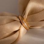 The Pave Curve Dome Ring with small diamonds rests on soft, beige fabric tied in a bow—an elegant piece perfect for your everyday jewelry stack.