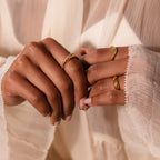 Close-up of hands with gold rings, including the Pave Curve Dome Ring in an everyday stack, worn with a sheer cream long-sleeve blouse.
