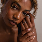 A woman with curly hair gently touches her face, wearing the Duo Form Ring Set in Silver on her finger.
