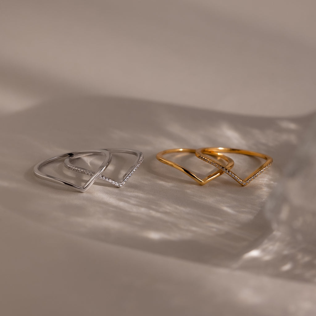 Four minimalist rings from the Curve Stacking Set, two in silver and two in gold, arranged on a neutral surface with soft shadows—ideal for a chic stacked look.