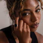 Woman with curly hair wearing a black top and the Midnight Hour Onyx Ring in Silver with an adjustable band, gazing softly at the camera.