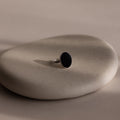 The Midnight Hour Onyx Ring, featuring a silver band and dark oval stone, is displayed on a smooth, light beige stone surface.