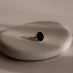 The Midnight Hour Onyx Ring, featuring a silver band and dark oval stone, is displayed on a smooth, light beige stone surface.