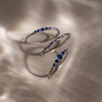 Three silver rings with blue gemstones on a textured surface