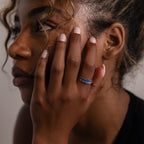 Close-up of a person with a hand on their face, wearing a set of 3 sapphire gemstone stacking rings.