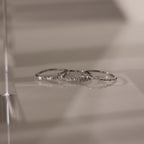 The Crystal Stacking Ring Set in Silver features three elegant rings with crystal gemstones, beautifully displayed on a smooth, reflective surface.