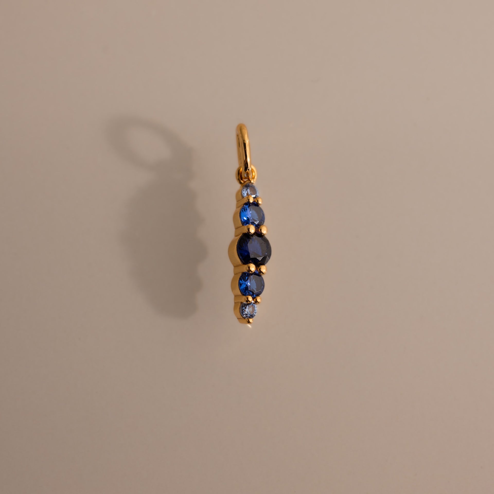 Ombre Lace Sapphire Charm pendant features five vertical blue sapphires on a neutral background with a soft shadow—ideal as a personalized charm or meaningful birth month gift.