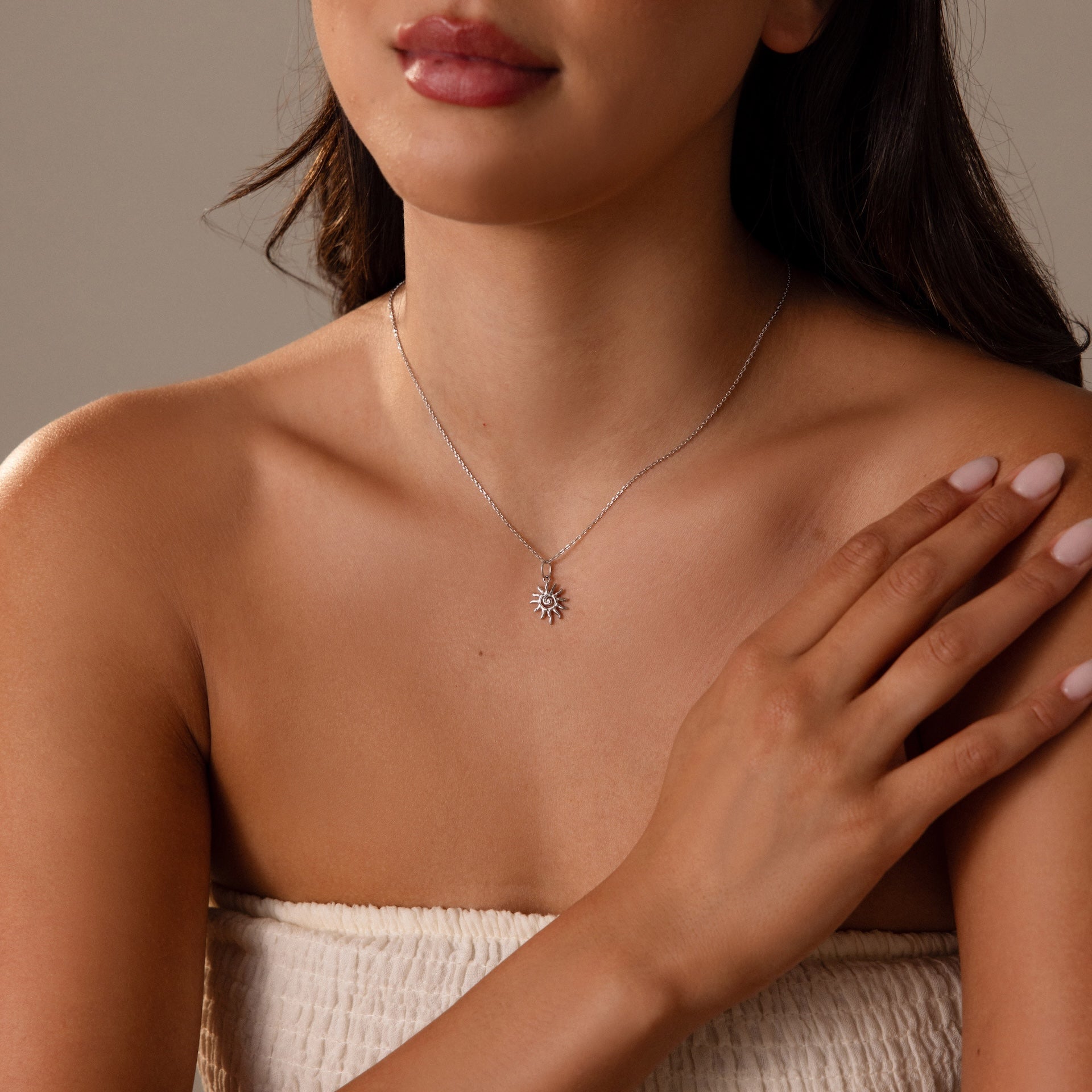 A woman in a strapless top touches her collarbone while wearing the Celestial Sun Necklace.