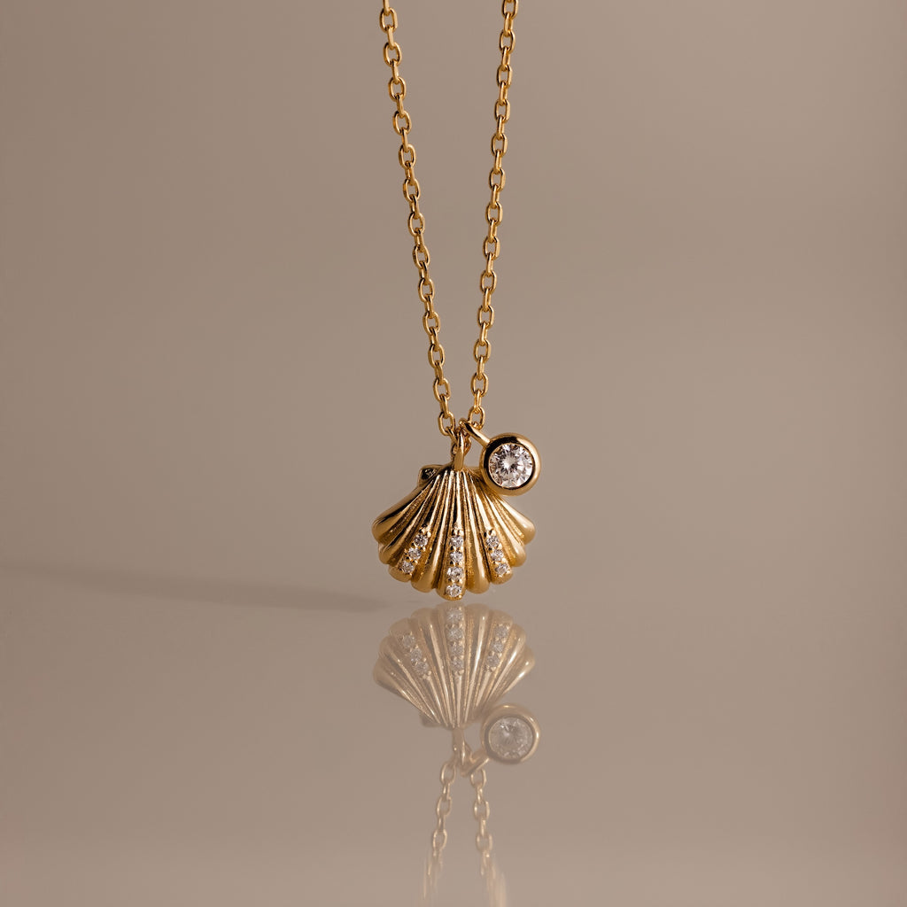 Diamond Seashell Charm Necklace in 18K Gold features a shell pendant and diamond charm, perfect for adding coastal style to any look.