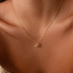 The Diamond Seashell Charm Necklace is a beautiful gold chain with a delicate seashell pendant, perfect for adding coastal charm to any womans style.