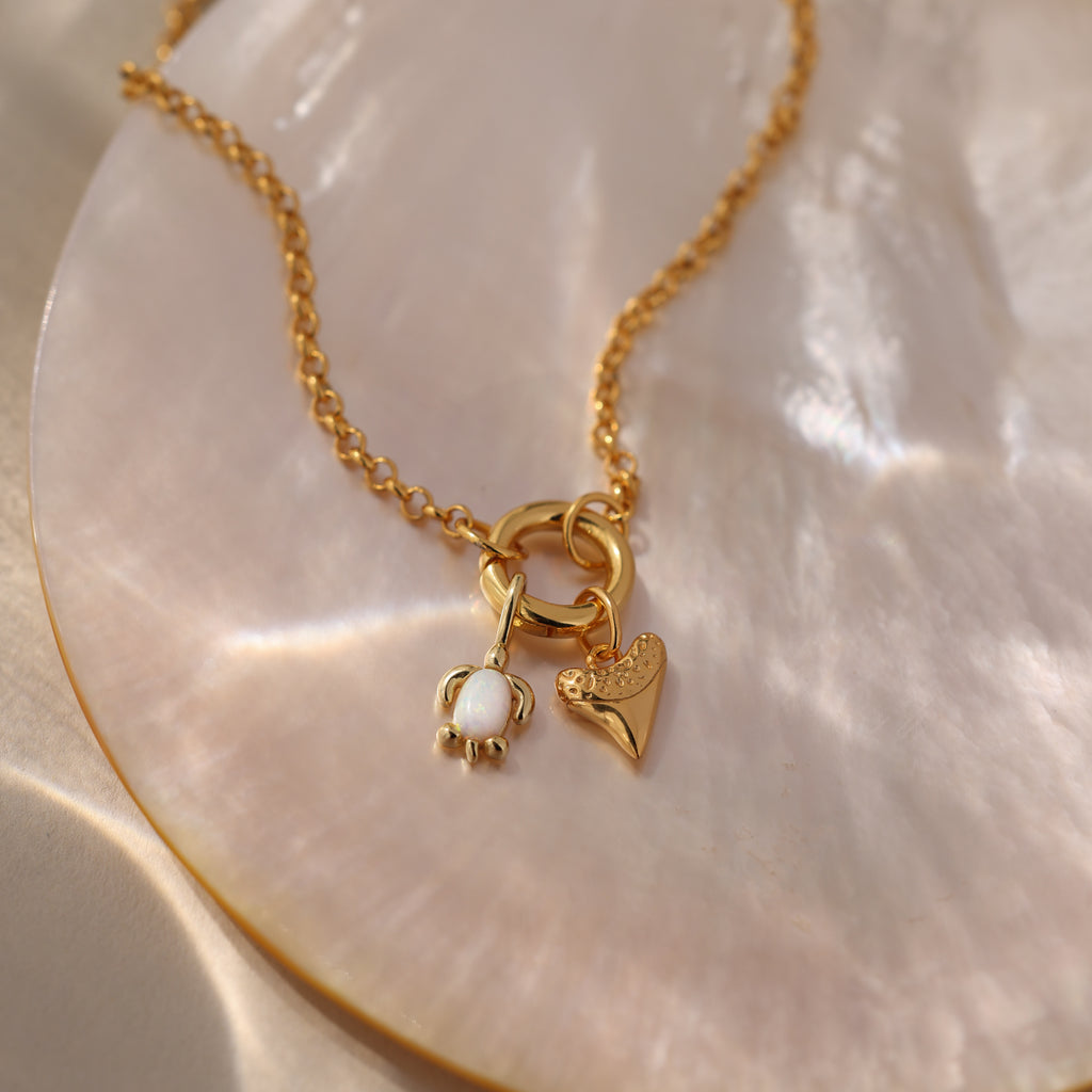 Gold chain necklace with an Opal Sea Turtle Charm on a shiny, iridescent surface—perfect for ocean-inspired, seaside jewelry lovers.