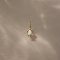 Opal Sea Turtle Charm in 18K Gold featuring an opal stone center, set against a soft beige background with ocean-inspired light reflections.
