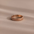 The Organic Fingerprint Band in Rose Gold, custom-engraved and displayed on a soft beige background, makes an elegant memorial keepsake to cherish forever.