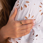 Moss agate ring worn on the hand, gently placed over a white broderie anglaise dress, showing the subtle sparkle of the baguette accents.