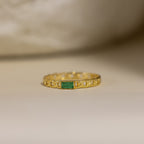 The Baguette Emerald Curb Ring features a rectangular bezel-set emerald on a curb-link band, showcased against a neutral background.