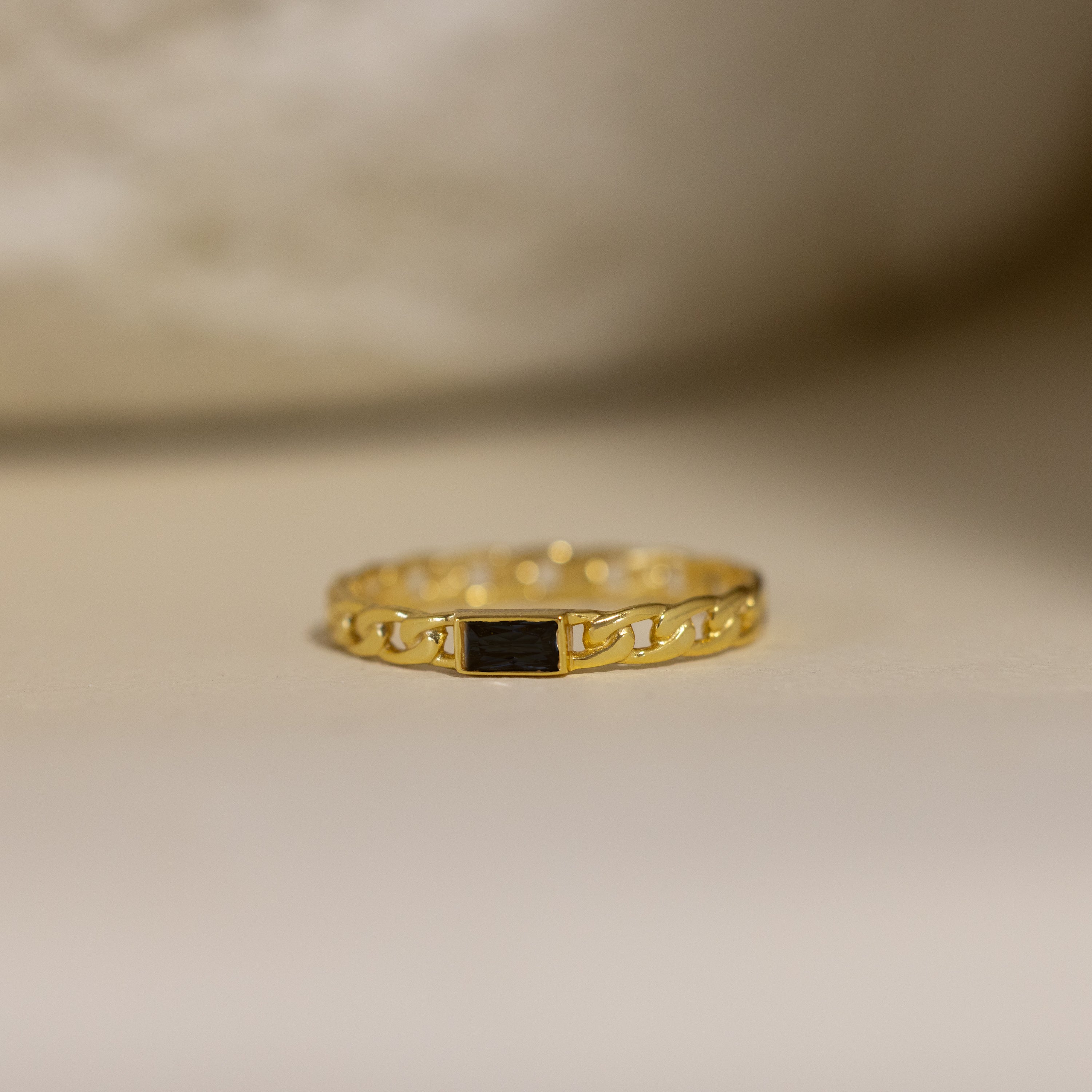 The Baguette Onyx Curb Ring showcases a slim curb-link band and a rectangular bezel-set black stone at the center.