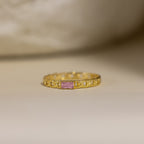 The Baguette Pink Tourmaline Curb Ring features a pink tourmaline baguette on a delicate, chain-inspired gold band, set against a soft background.