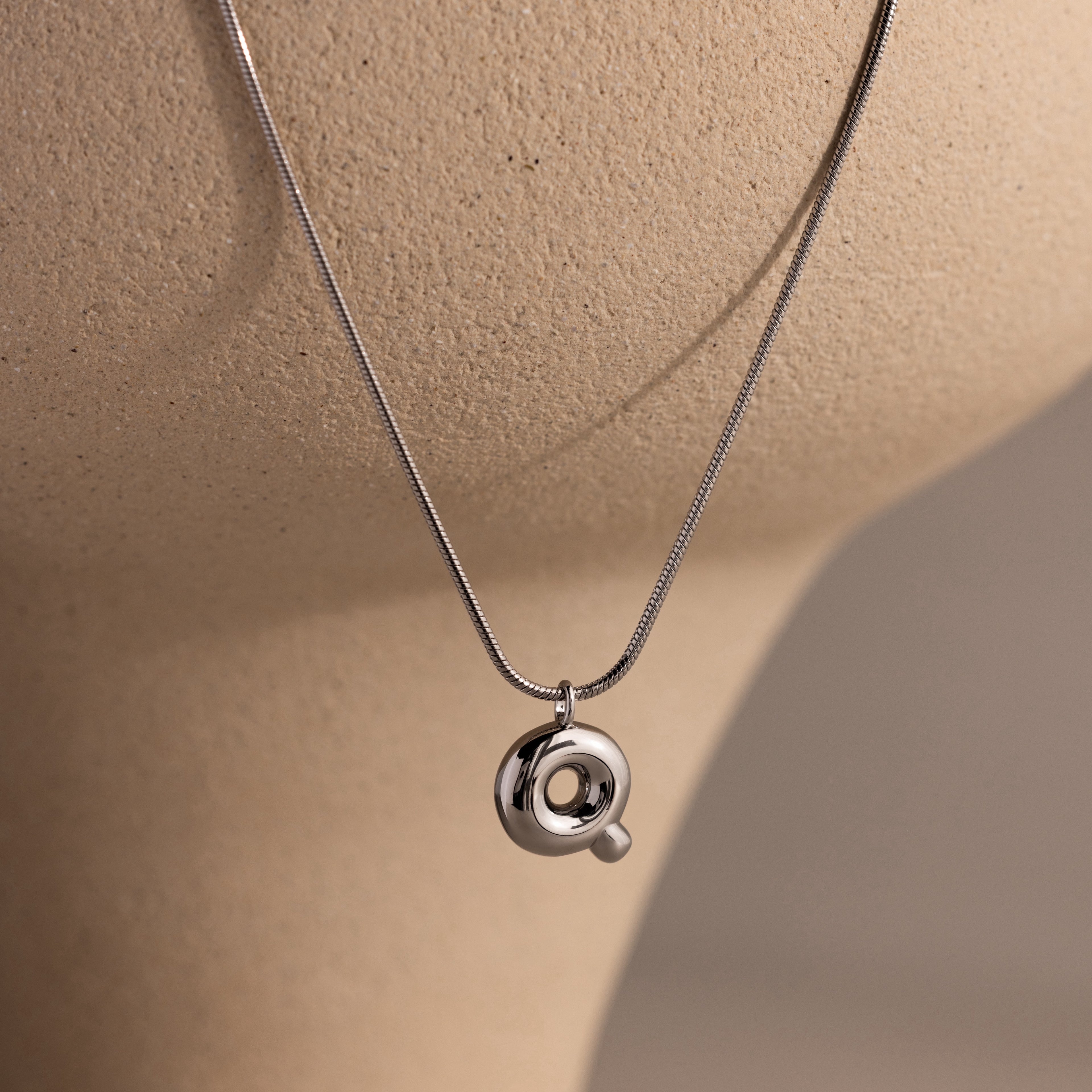 Bubble Letter Necklace in White Gold displayed on a beige mannequin bust against a neutral background, perfect for those who love personalized jewelry.