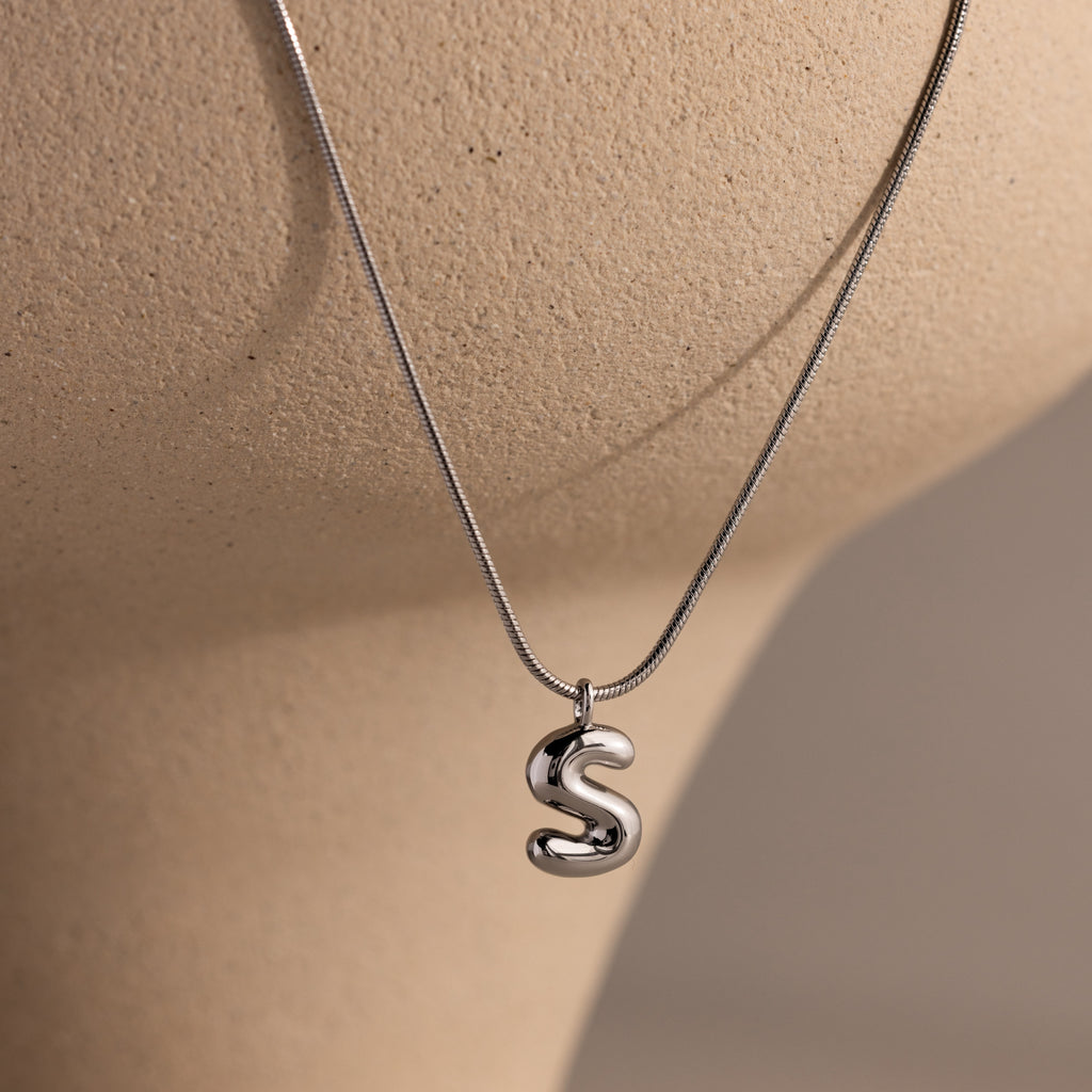 Bubble Letter Necklace in White Gold featuring an S pendant, showcased on a light beige mannequin bust—ideal for anyone who loves personalized jewelry.