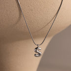 Bubble Letter Necklace in White Gold featuring an S pendant, showcased on a light beige mannequin bust—ideal for anyone who loves personalized jewelry.