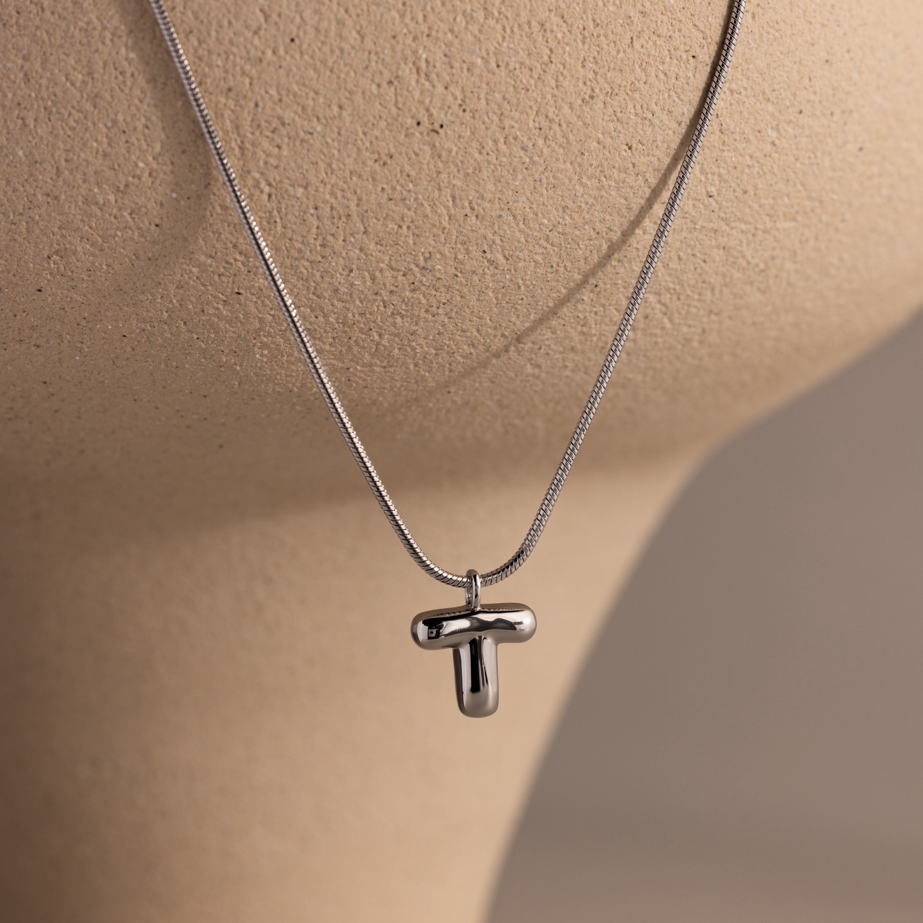 Bubble Letter Necklace in White Gold displayed on a beige mannequin bust, perfect for fans of personalized jewelry with a modern touch.