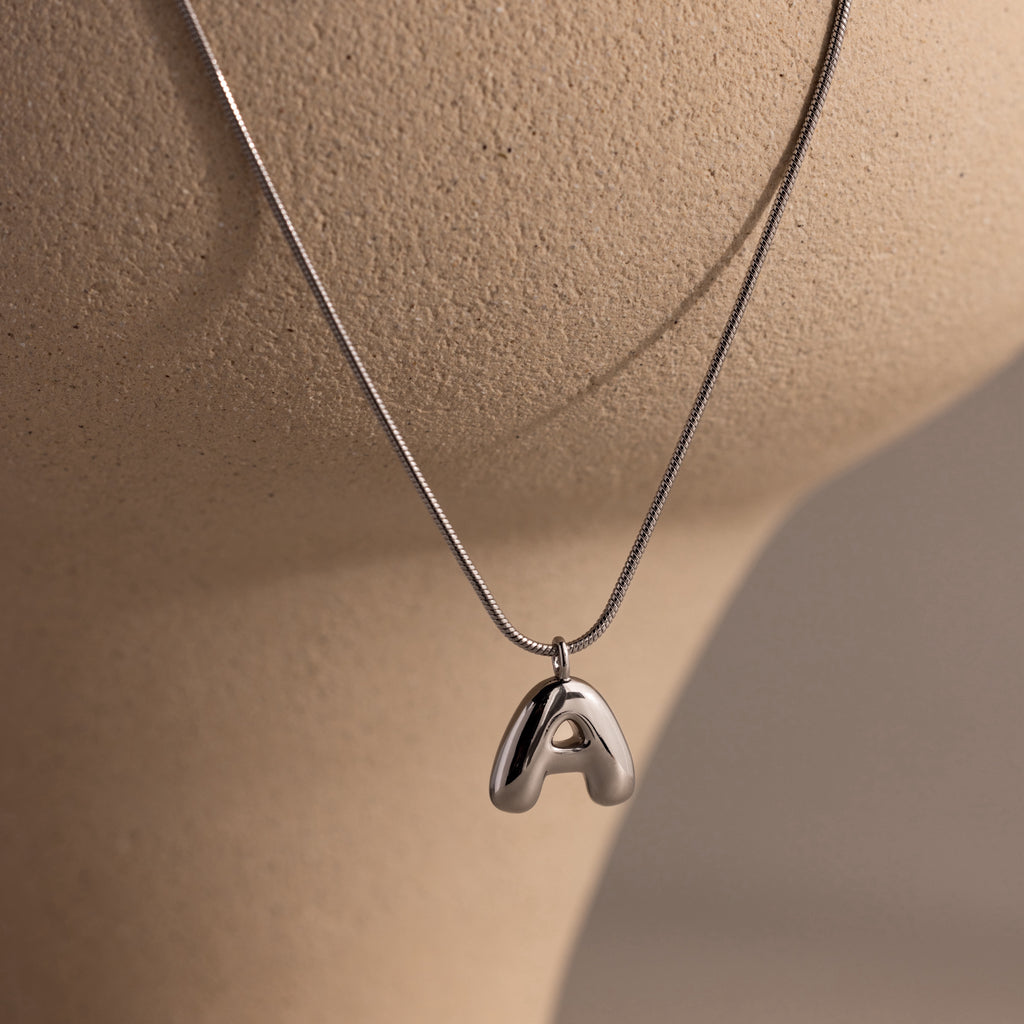 Bubble Letter Necklace in White Gold with a polished letter A pendant, displayed on a beige mannequin bust—perfect as personalized jewelry for any occasion.