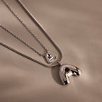 Two Dainty Bubble Letter Necklaces in Sterling Silver with shiny letter A pendants rest on a soft beige background—an elegant, personalized accessory for any style.