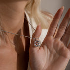 A close-up of a person holding the Bubble Letter Necklace in White Gold near their face, highlighting the charm and elegance of this personalized jewelry piece.