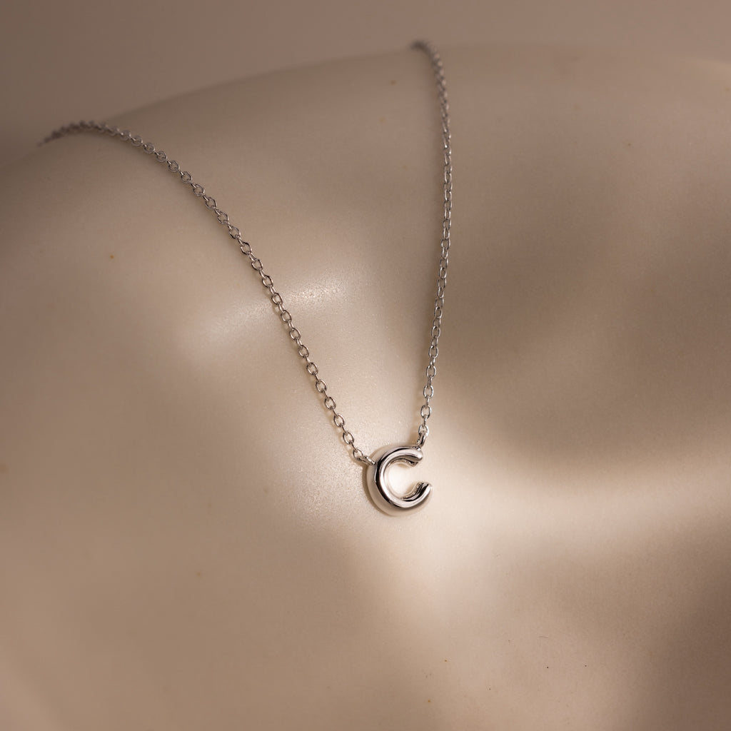 A Dainty Bubble Letter Necklace in Sterling Silver rests on smooth, light-toned skin.