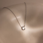 A Dainty Bubble Letter Necklace in Sterling Silver rests on smooth, light-toned skin.