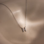 The Dainty Bubble Letter Necklace in Sterling Silver features a minimalist H pendant that rests beautifully on light skin, offering a personalized touch to any outfit.