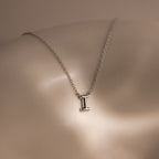 The Dainty Bubble Letter Necklace in Sterling Silver features a minimalist pendant shaped like the letter I, displayed on a smooth, neutral background.