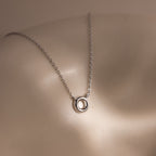 Dainty Bubble Letter Necklace in Sterling Silver featuring a bubble letter pendant, displayed on a smooth, curved surface under soft lighting.