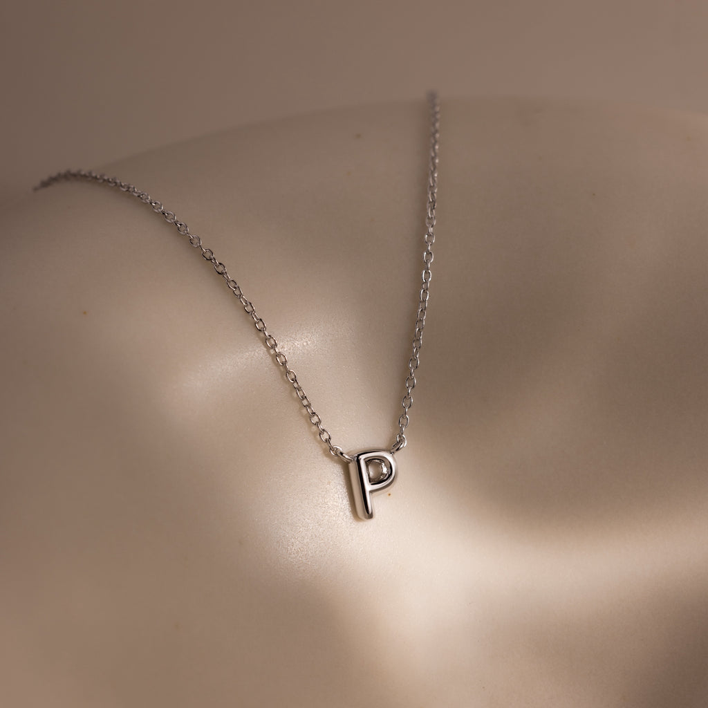 The Dainty Bubble Letter Necklace in Sterling Silver features a sleek letter P pendant, resting gracefully on the skin—a perfect personalized accessory for any occasion.