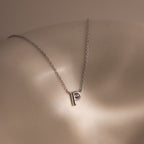 The Dainty Bubble Letter Necklace in Sterling Silver features a sleek letter P pendant, resting gracefully on the skin—a perfect personalized accessory for any occasion.