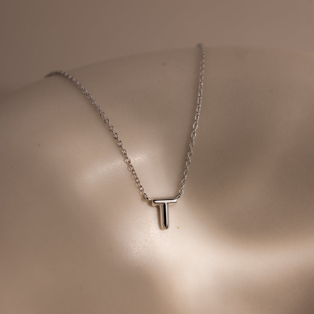 Dainty Bubble Letter Necklace in Sterling Silver, featuring a personalized initial pendant on a sleek silver chain, elegantly displayed on a smooth, neutral surface—ideal for lovers of minimalist and custom jewelry.