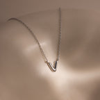 A Dainty Bubble Letter Necklace in Sterling Silver rests on smooth, light-colored skin under soft lighting.
