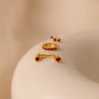 The Opal Earring Trio Set is showcased on a smooth, beige surface under soft lighting.