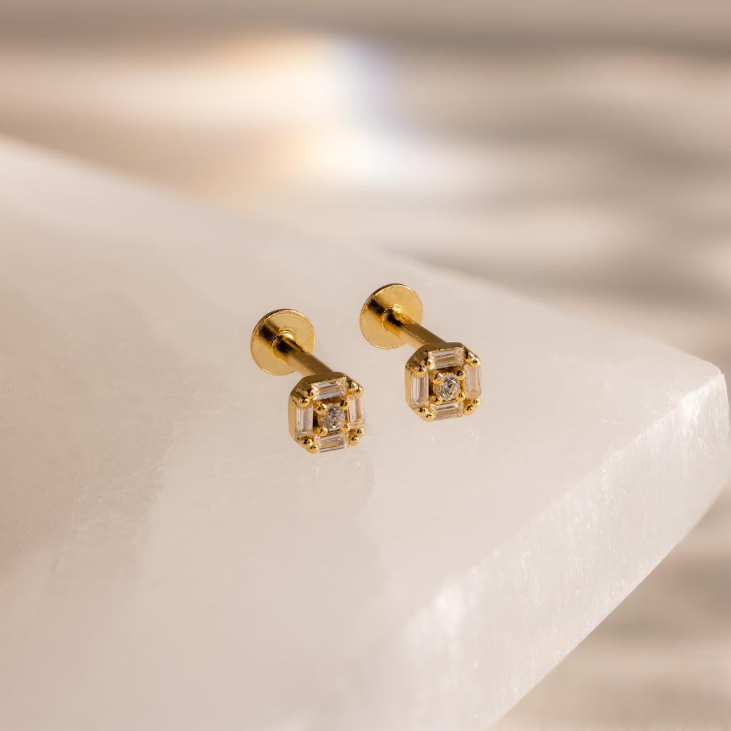 Pair of gold flatback earrings with vintage-inspired square diamond design on white marble.