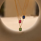 Three North Star Birthstone Necklaces with gold chains and rectangular crystal pendants in pink, blue, and green, each adorned with a diamond-set North Star design.