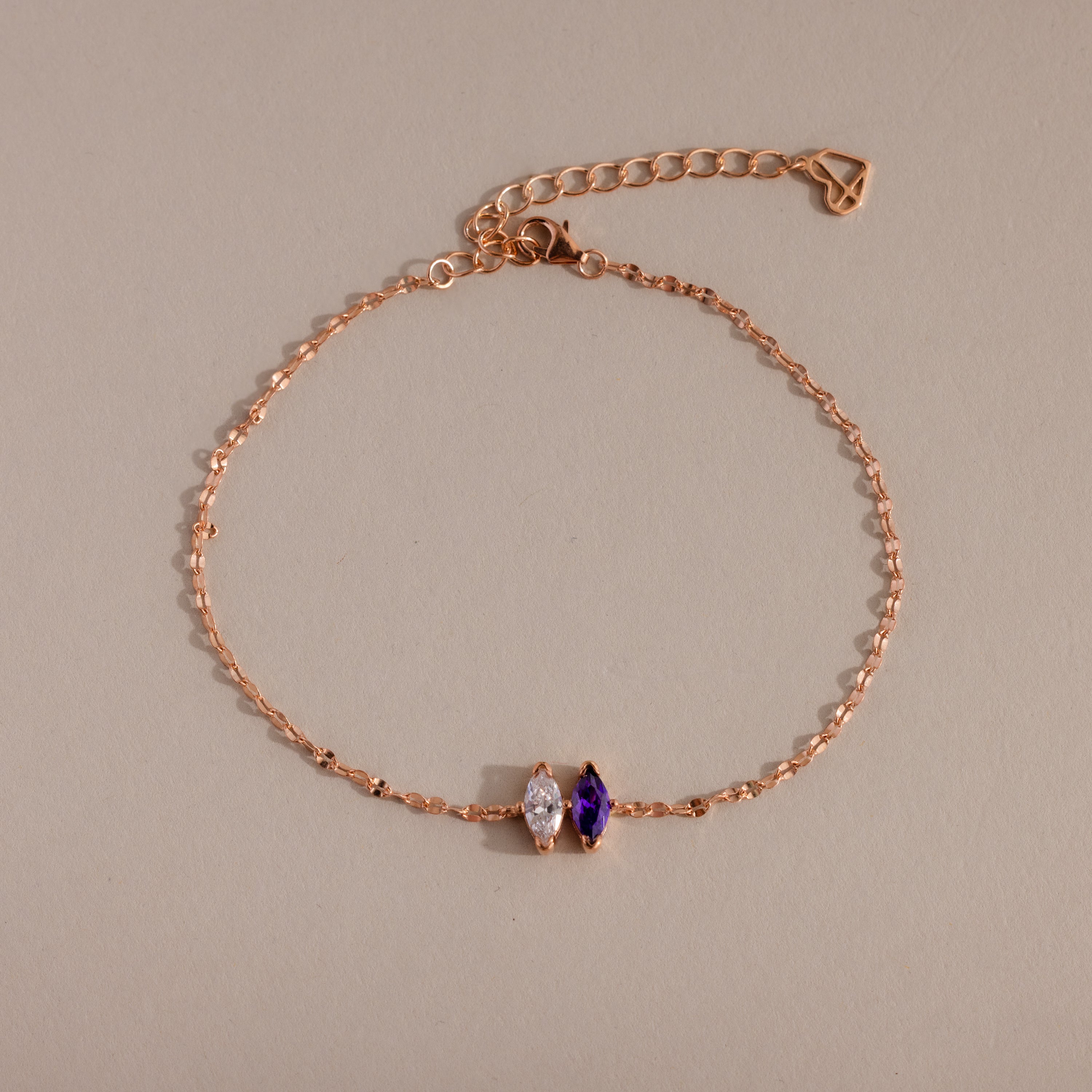 Multiple Marquise Birthstone Bracelet in Rose Gold with clear and purple gemstones, shown on a beige background—an ideal customizable piece for adding a personal touch.