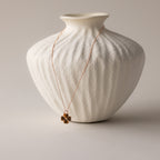 Tiger's Eye Clover Necklace draped over a textured white ceramic vase on a neutral background, perfect as a lucky pendant for any occasion.