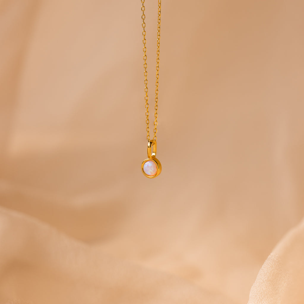 Signet Birthstone Charm in Opal / October, displayed on soft beige fabric—a refined piece that highlights the captivating beauty of opal gemstone charms and the appeal of personalized jewelry.
