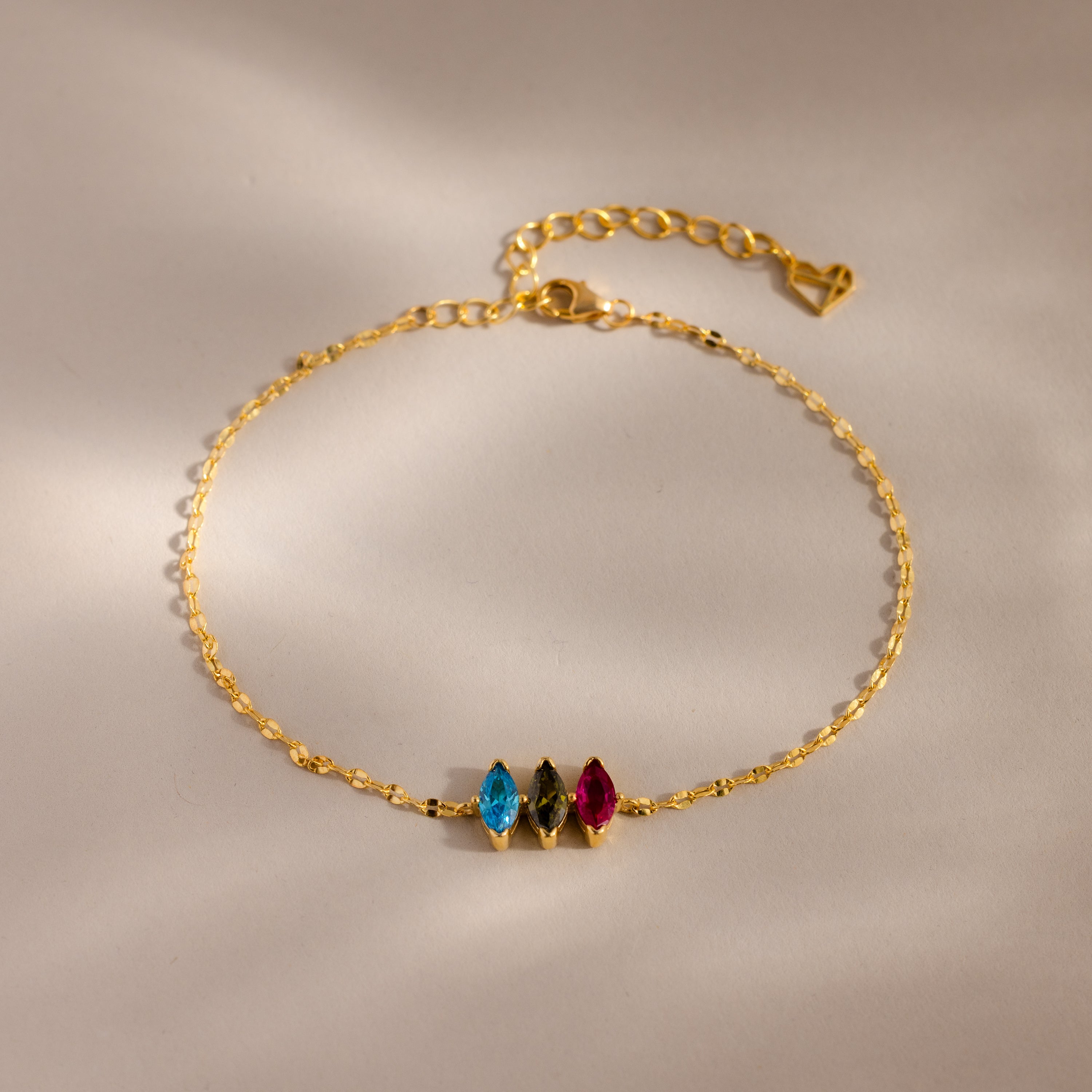 The Multiple Marquise Birthstone Bracelet in 18K Gold features blue, green, and pink gemstones on a light neutral background—an elegant customizable bracelet perfect for birthstone jewelry lovers.