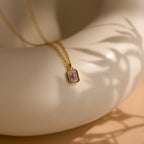 The North Star Birthstone Necklace in Alexandrite (June) rests elegantly on a smooth, cream-colored curved surface, showcasing its radiant charm.
