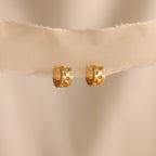 Pave Checkered Huggies—gold hoop earrings with small square diamond accents—displayed on beige fabric against a neutral background.