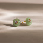 Close-up of round green jade stud earrings featuring a sparkling CZ diamond center and gold bezel setting, displayed on a neutral background.