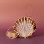 The Thin Pink Jade Bangle Set is artfully arranged with a seashell and bar of soap on a pink gradient background.